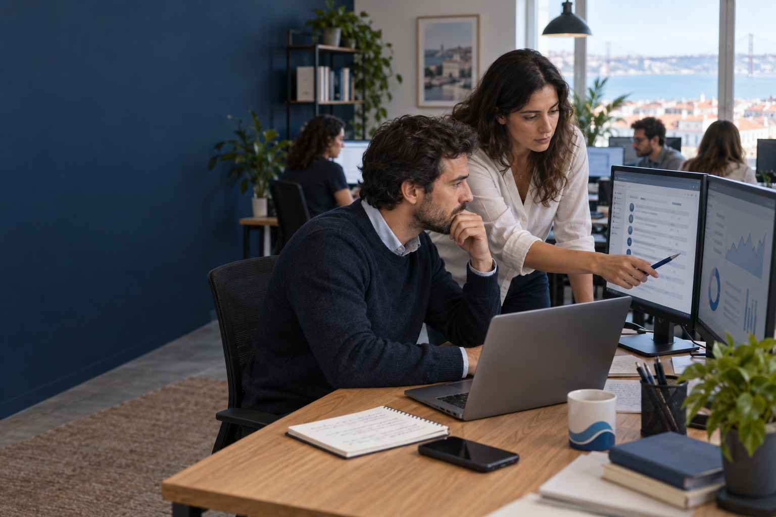 Two small-business colleagues review account activity and an email-security alert in a calm office after a suspected phishing incident.